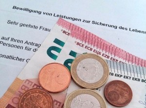 Amtlicher Brief „Bewilligung von Leistungen“, darauf Münzen und Scheine.