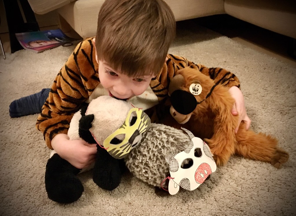 Kind mit Stofftieren, die Tiermasken tragen.