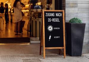 Holztafel vor Lokal mit Aufschrift „Zutritt 2G: Genesen und geimpft“