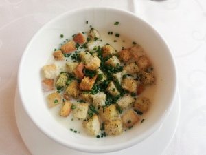 Teller mit Kartoffelsuppe und Croûtons, von oben fotografiert.