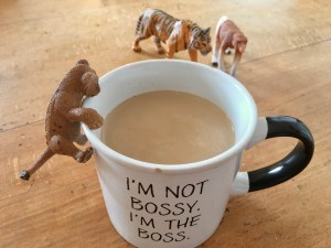 Plastiktier „Löwe“ klettert an Kaffeetasse mit der Aufschrift „I‘m not bossy, I‘m the boss“ hoch.