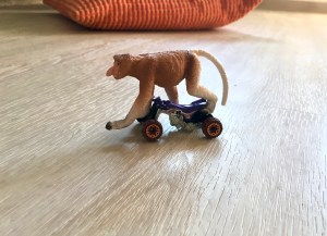 Plastiktier „Nasenaffe“ skatet auf Spielzeug-Auto.