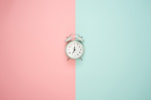 Wecker vor rosa-hellgrünem Hintergrund.