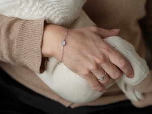 Frauenhand mit Muttermilchschmuck und Baby
