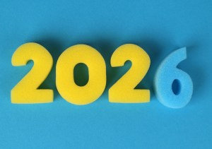 Jahreszahl 2026, gebildet aus Spülschwämmen vor blauem Hintergrund.